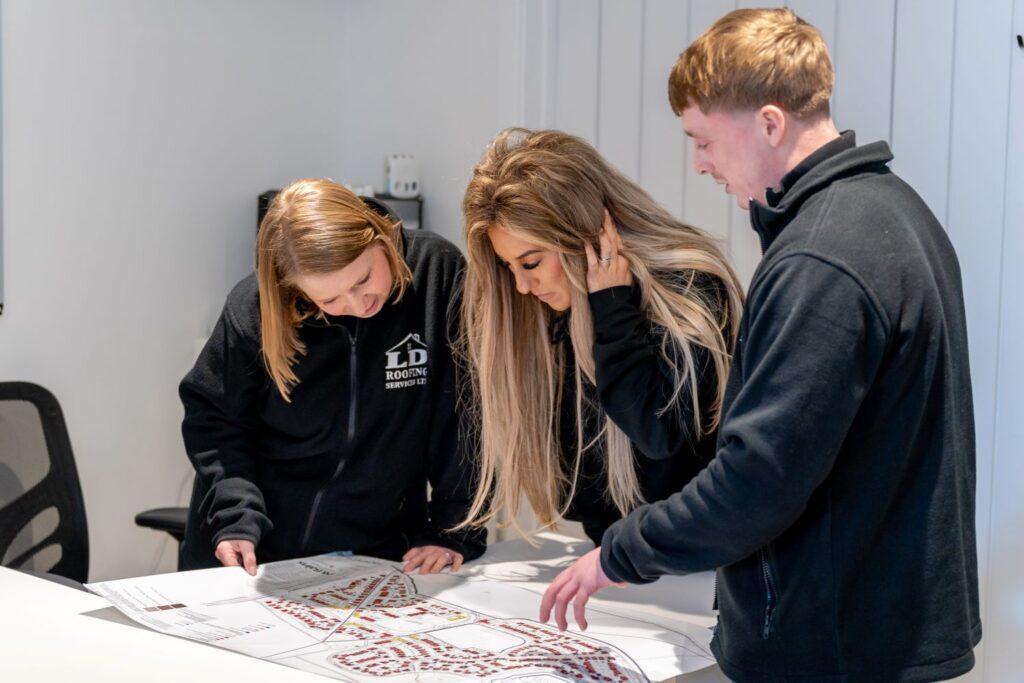 image of three ld roofing employees pointing at a building map