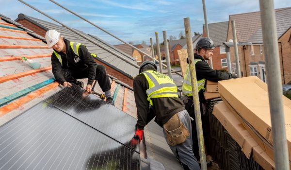 image of three ld roofing workers installing solar panels on a roof
